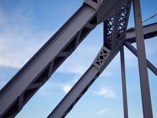 Detail of painted riveted bridge against blue sky.