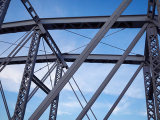 Detail of painted riveted bridge against blue sky.