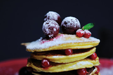 Stack of pancakes with berries and sugar powder