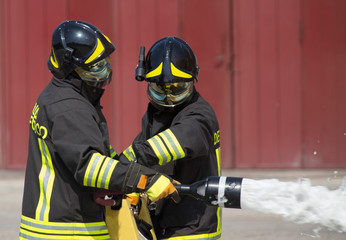 Obraz premium two firemen in action with foam