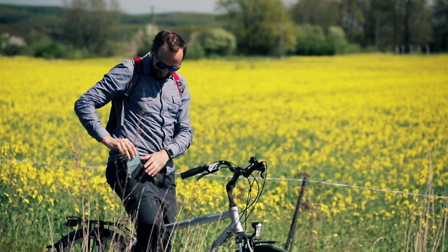 Young, handsome man take a picture of a rape seed field
