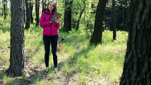 Lost, pretty woman looking for direction on tablet in the forest
