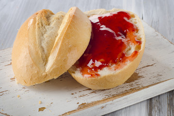 Slice of bread with strawberry jam on a white  wooden cutting bo