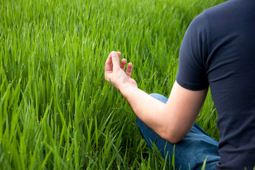 Man sits in the middle of a green meadow