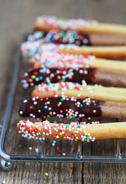sweet bread sticks with chocolate and colorful sprinkles on a wi