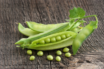 Pods of green peas on a wooden surface