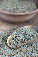 Dry green french lentils (Du Puy) in a clay bowl and in a scoop