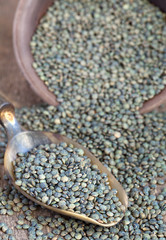 Dry green french lentils (Du Puy) in a clay bowl and in a scoop