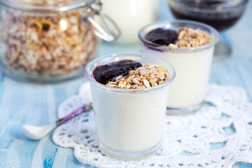 Small jar with homemade yogurt with blackcurrant jam and granola