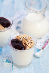 Small jar with homemade yogurt with blackcurrant jam and granola