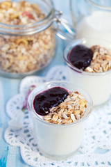 Small jar with homemade yogurt with blackcurrant jam and granola