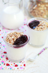 Small jar with homemade yogurt with blackcurrant jam and granola