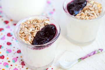 Small jar with homemade yogurt with blackcurrant jam and granola