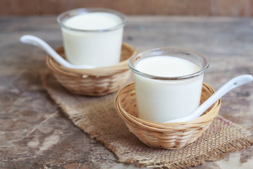 Fototapeta na wymiar Two small jars homemade yogurt in a wicker baskets