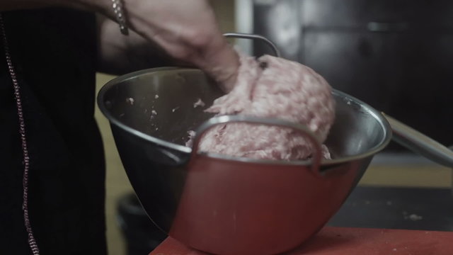 Cook mixing forcemeat in a metal aluminium bowl