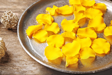 Rose petals in bowl on wooden background