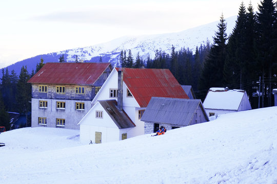 Building with red roof over snow and Carpathian Mountains in wintertime