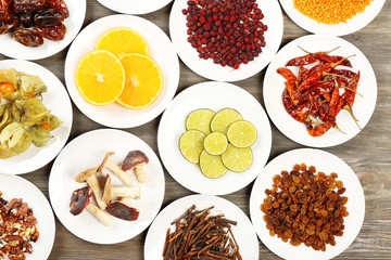Different products on saucers on wooden table, top view