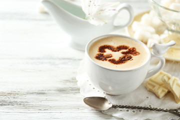 Cup of latte coffee art on wooden table, on light background