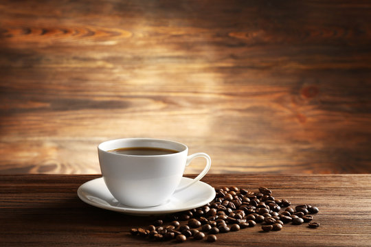 Cup of coffee with grains on wooden background © Africa Studio