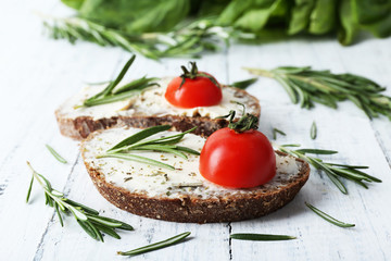 Delicious sandwiches with tomatoes and greens on wooden background