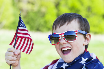 4th of july holiday: happy boy in sunglasses holding  American flag 