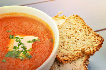 Tomato soup with basil and fresh black bread closeup
