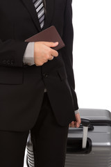 Business traveling pulling suitcase and holding passport