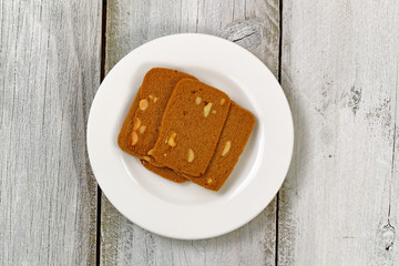 Wafer shaped cookies in plate on aged white wood