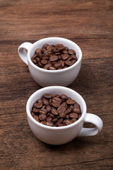 Fototapeta na wymiar cup of coffee beans on the brown wooden background