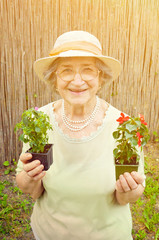 Happy senior woman holding flowers in garden