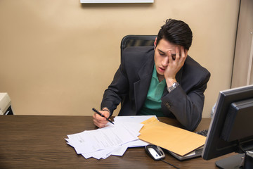Tired bored young businessman sitting in office yawning