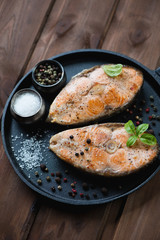 Roasted salmon steaks with various spices and green basil leaves