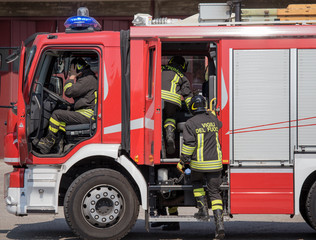 Italian firefighters climb on firetrucks during an emergency