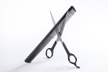 Scissors and comb standing on a table isolated