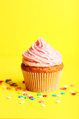 Birthday cupcake with butter cream on yellow background