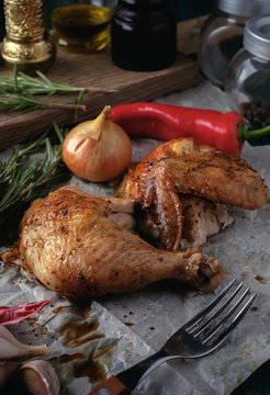 Roasted chicken leg and wing with spices and herbs on a wooden t