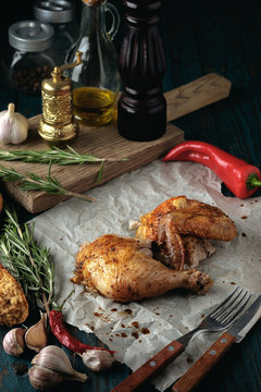Roasted chicken with spices and herbs on a wooden table.