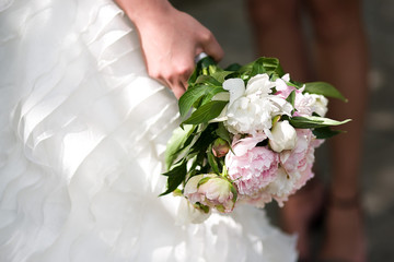 Gentle wedding bouquet with peonies in hands of the bride