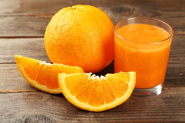 Orange fruit and glass of juice on brown wooden background