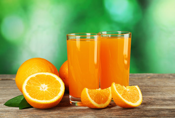 Glass of fresh orange juice on grey wooden background