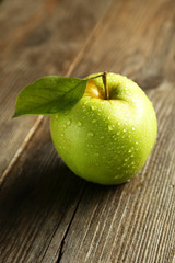Green apple with leaf on brown wooden background