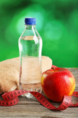 Red apple with measuring tape and bottle of water 