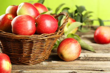 Apples in basket on brown wooden background