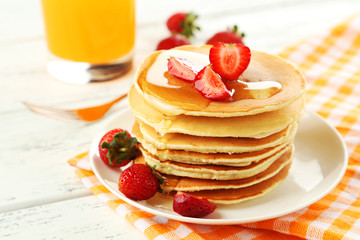 Delicious pancakes with strawberry on white wooden background