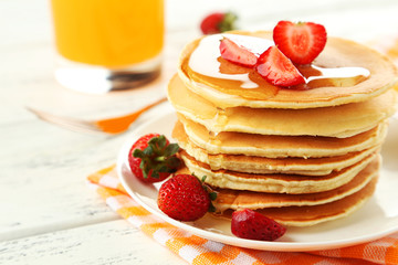 Delicious pancakes with strawberry on white wooden background