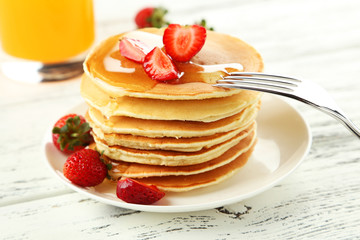 Delicious pancakes with strawberry on white wooden background