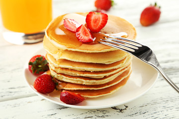 Delicious pancakes with strawberry on white wooden background