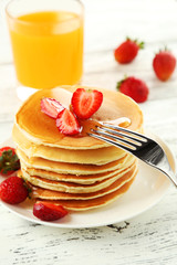 Delicious pancakes with strawberry on white wooden background