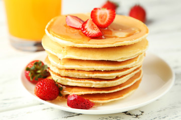 Delicious pancakes with strawberry on white wooden background